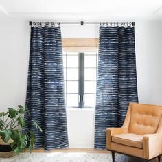 a living room filled with furniture and a large window covered in blue striped drapes