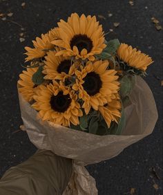 a bouquet of sunflowers wrapped in brown paper