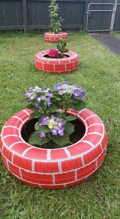 three flower pots made out of old tires in the grass with flowers growing from them