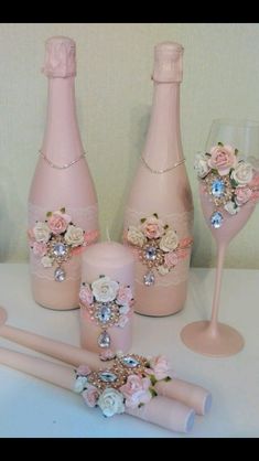 three pink wine bottles with flowers on them and two champagne flutes in the foreground