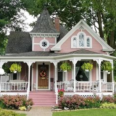 a pink and white house with flowers on the front porch