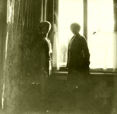 an old photo of two women standing in front of a window