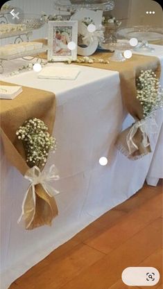 the table is decorated with baby's breath flowers and burlap ribbon for decoration