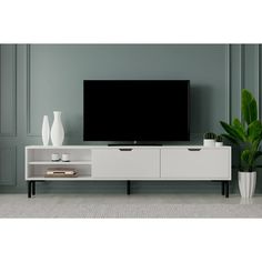 a white entertainment center with a flat screen tv on it's stand and two vases next to it