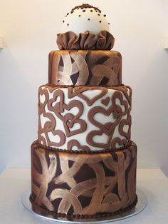 a three tiered cake is decorated with brown and white designs