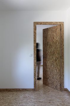 a person standing in an open door to a room with plywood on the walls