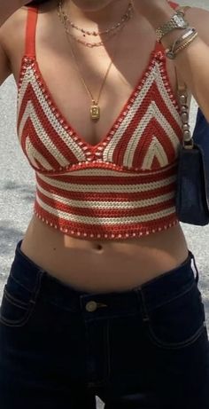 a woman wearing a red and white top talking on a cell phone while standing in the street