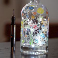 a glass bottle sitting on top of a table next to a pen