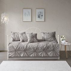 a white daybed with four pillows and two pictures on the wall