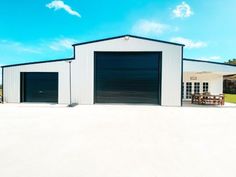 a white building with two garages and a picnic table