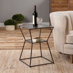 a glass table with a bottle of wine on it in front of a beige chair