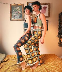 two women standing on top of a bed next to each other wearing crocheted clothing