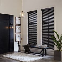 a living room with black shuttered windows and a white rug on the wooden floor