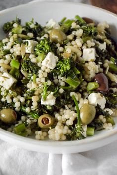 a white bowl filled with rice, broccoli and olives on top of a table