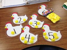 four chickens with numbers on them sitting on a table next to a bag of candy