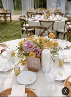 a table set up with flowers and candles for an outdoor wedding reception at the park