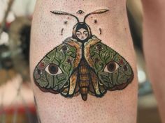 a close up of a person's leg with a moth tattoo on the thigh