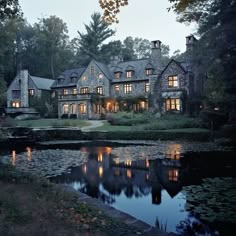 a large house sitting on top of a lush green hillside next to a lake at night