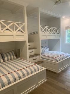 two bunk beds in a room with white walls and wood flooring, one has blue and white striped bedding