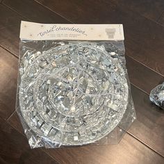 a glass plate sitting on top of a wooden floor next to a package of silver foil