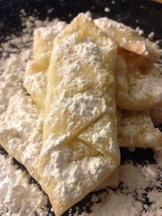 some type of pastry on a black plate with powdered sugar around it and another item in the background