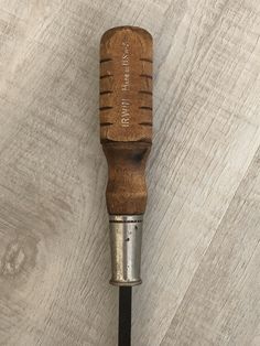 a close up of a wood and metal object on a wooden surface with a screwdriver