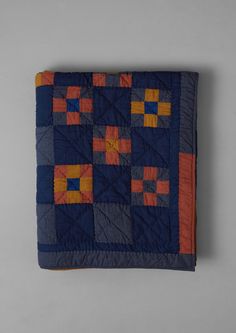 a blue and orange quilted blanket with squares on it's sides, sitting on a gray surface