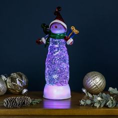 a lighted snowman figurine sitting on top of a table next to ornaments