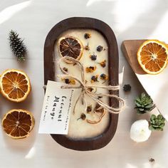 an orange slice is tied up with twine and sits on a tray next to other fruit