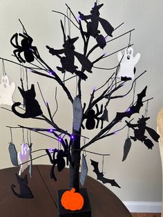 a halloween tree with bats and cats hanging from it's branches on a table