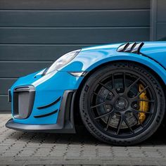 a blue sports car parked in front of a garage door