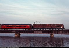 a red train traveling across a bridge over water