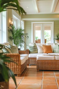 a living room with wicker furniture and potted plants on the side table in front of it