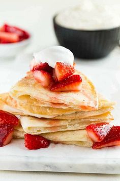 stack of pancakes topped with strawberries and whipped cream