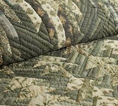 an old quilted bed spread with brown and green patterns