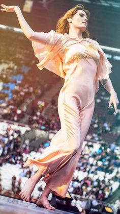 a woman standing on top of a stage with her arms out in front of the audience