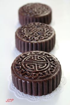 three chocolate cookies sitting on top of a white doily