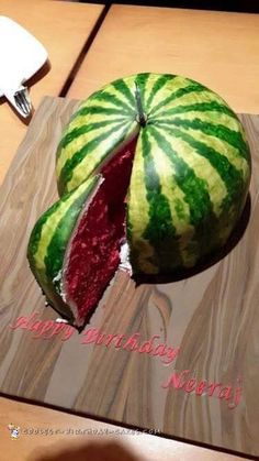 a watermelon is cut in half on a cutting board with the word happy birthday next to it