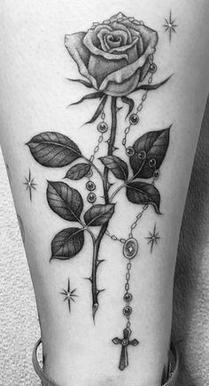 a rose with rosary and cross tattoo on the side of a woman's leg