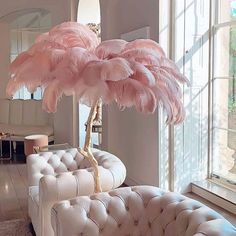 a living room filled with furniture and a large pink bird on top of a tree