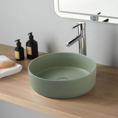 a bathroom sink sitting on top of a wooden counter next to a brush and soap dispenser