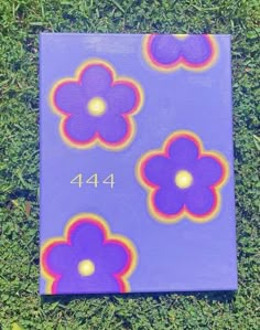 a purple canvas with flowers painted on it in the middle of some green grass,