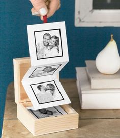 a person is placing pictures on top of a wooden box with two photos inside it