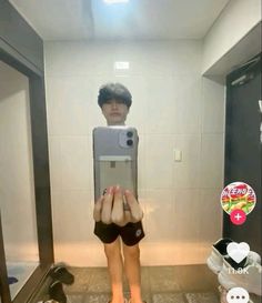 a woman taking a selfie in the bathroom with her cell phone and wearing shorts