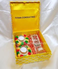 an open yellow box filled with assorted items on top of a white cloth covered bed