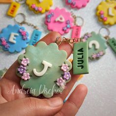 a hand holding a keychain shaped like an animal with flowers and letters on it