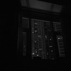 a window in a dark room with the city lights seen from it's windows