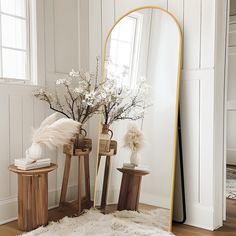 a large mirror sitting on top of a wooden table next to a vase filled with flowers