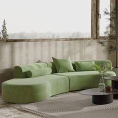 a living room with a large green couch and coffee table in front of a window