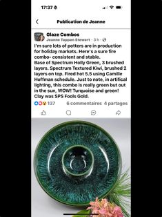 a green glass bowl sitting on top of a table next to a vase filled with flowers